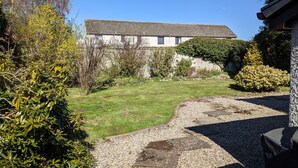 Ein Haus mit geneigtem Dach, umgeben von einem gepflegten Garten mit einem Kiesweg, der zum Eingang führt.