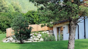 A house with a stone wall, wooden fence, and a tree in the front yard.