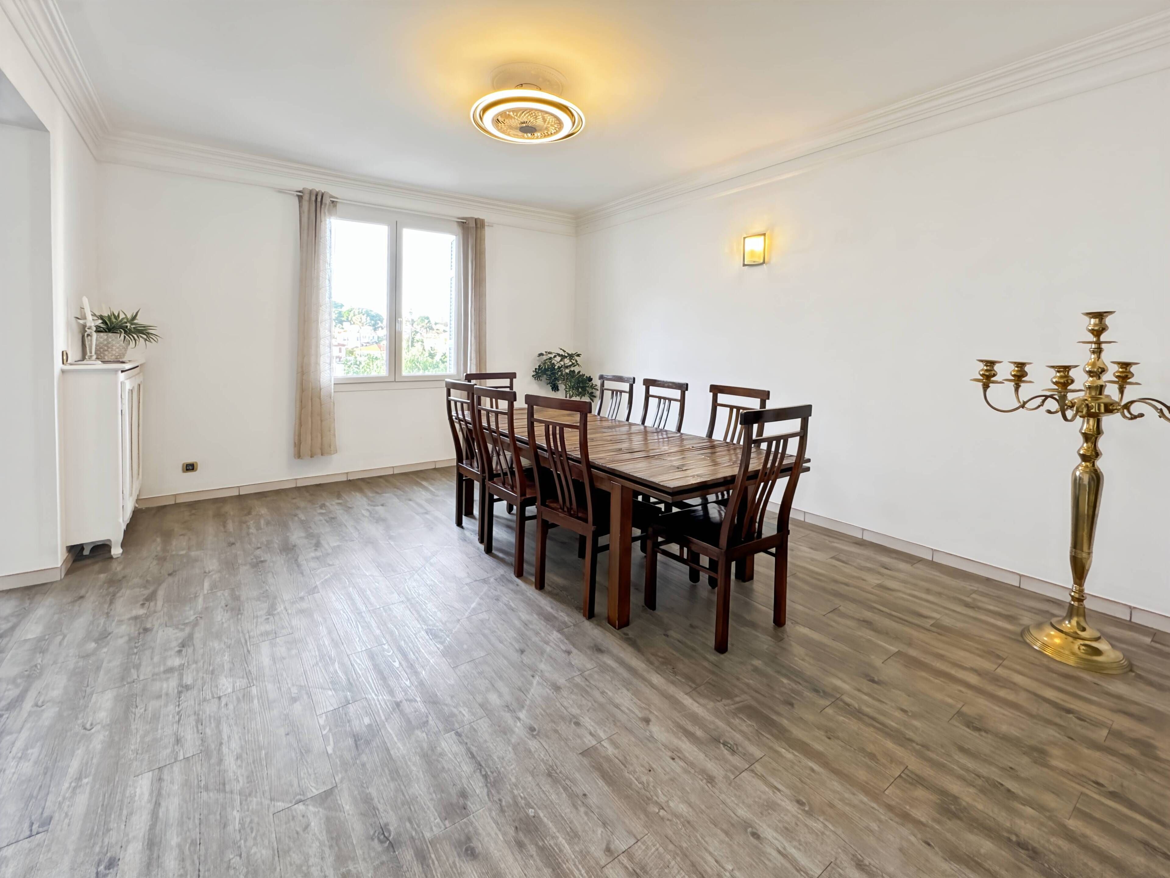 A dining area with a wooden table and chairs, a candelabra, and a wall-mounted light fixture.