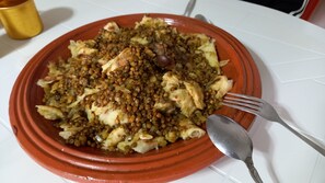 Un plato de comida con lentejas y verduras sobre un plato rojo.