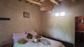 Quarto com uma cama, luminária pendente e janela.