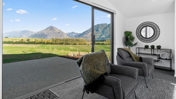 Ein modernes Wohnzimmer mit einem großen Schiebeglastür, die auf einen Balkon mit Bergblick führt.
