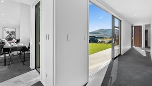 Ein modernes Interieur mit Essbereich, eine große Glasschiebetür mit Blick auf eine grüne Landschaft und Berge.