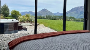 Ein Schlafzimmer mit großem Fenster, einer Whirlwanne und Bergblick.