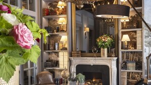 A room with a checkered floor, a fireplace, a chandelier, and bookshelves filled with books. - Hôtel & Spa Vinci Due (Paris)