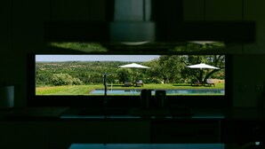A view through a window of a poolside area with two umbrellas and lounge chairs. - MONTE DA FIFAS Countryside house with a pool and a magnificent view over the dam (Montargil)