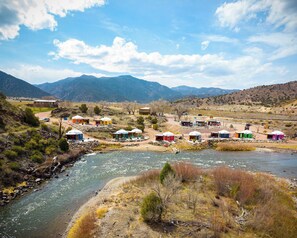 A riverside village with yurts and cabins, surrounded by mountains. - Blue Heron (Cañon City)
