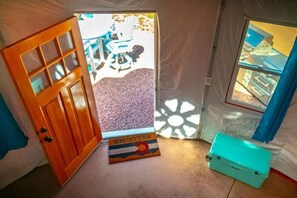 A room with a wooden door, a window, and a welcome mat.