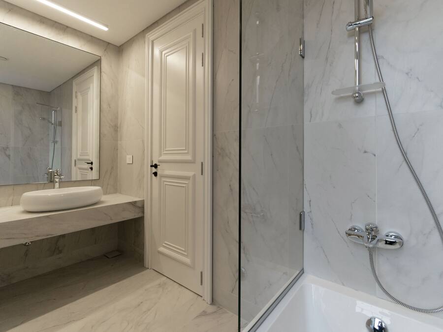Un bagno moderno con lavabo in marmo, uno specchio grande e cabina doccia in vetro.
