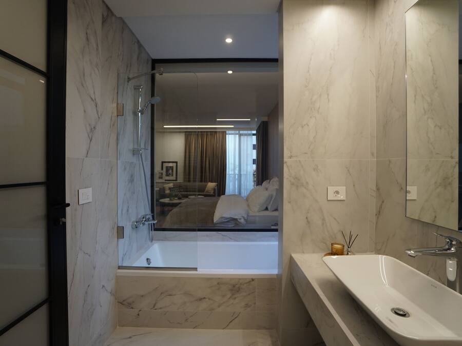 A modern bathroom with a large mirror, a bathtub, and a vanity with a sink.