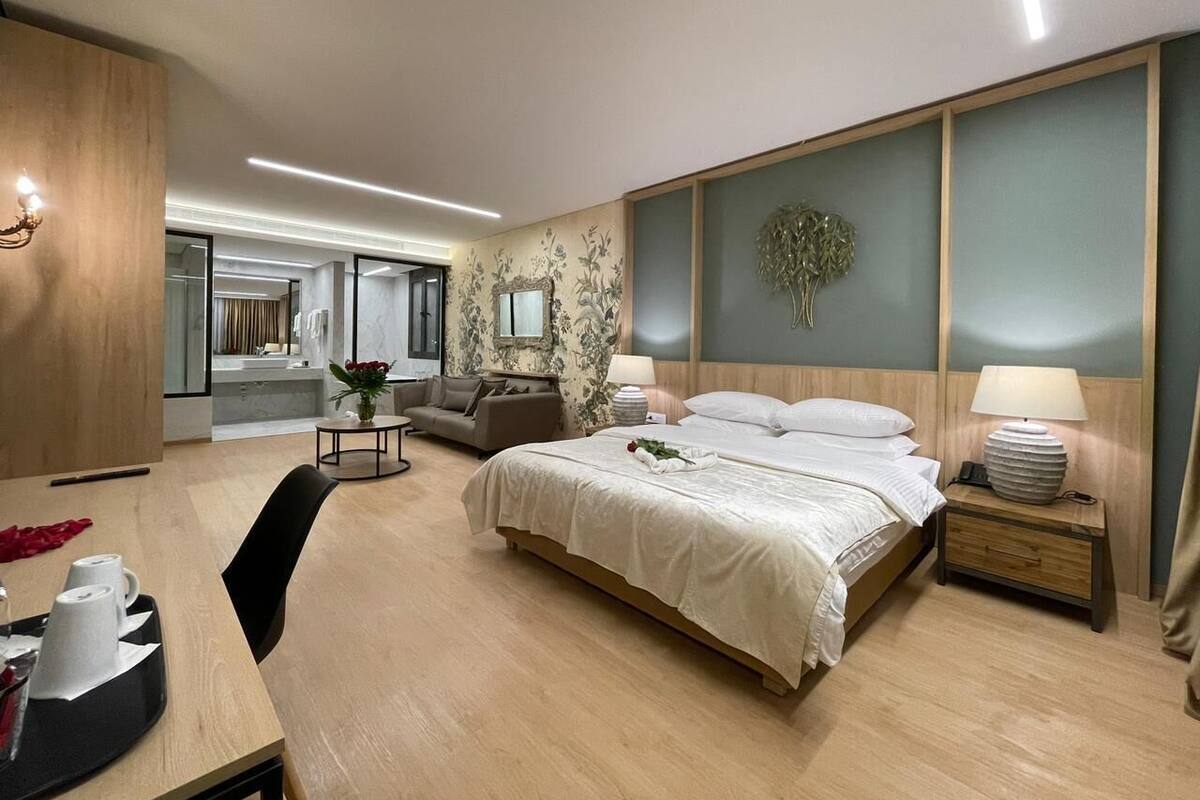 A modern hotel room with a large bed, a desk, and a sofa.