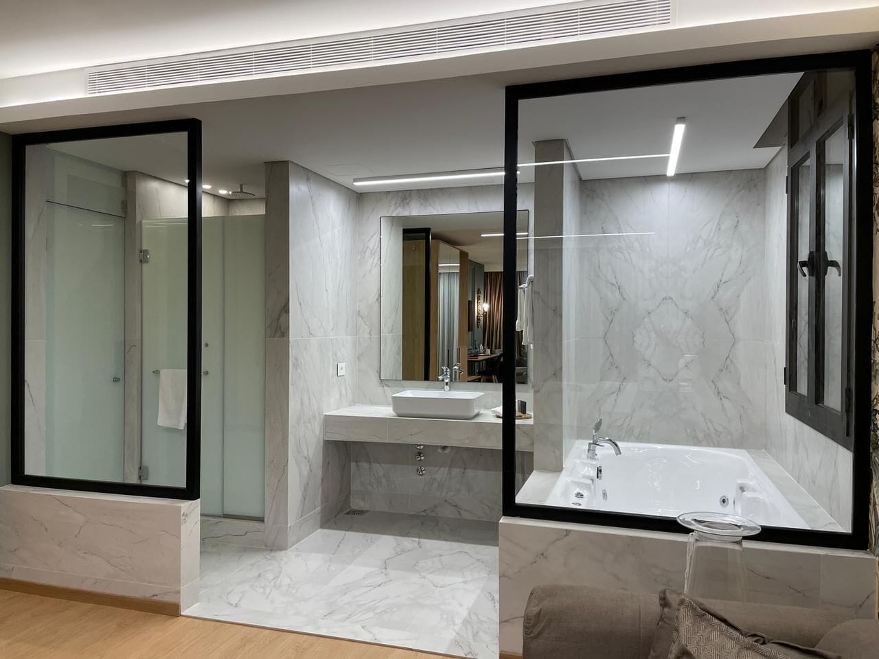 Un baño moderno con ducha envuelta en vidrio, bañera independiente y tocador con espejo.