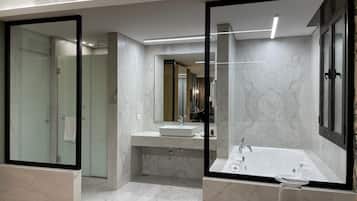 Un baño moderno con ducha envuelta en vidrio, bañera independiente y tocador con espejo.