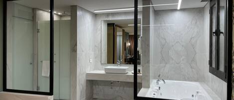 Un baño moderno con ducha envuelta en vidrio, bañera independiente y tocador con espejo.