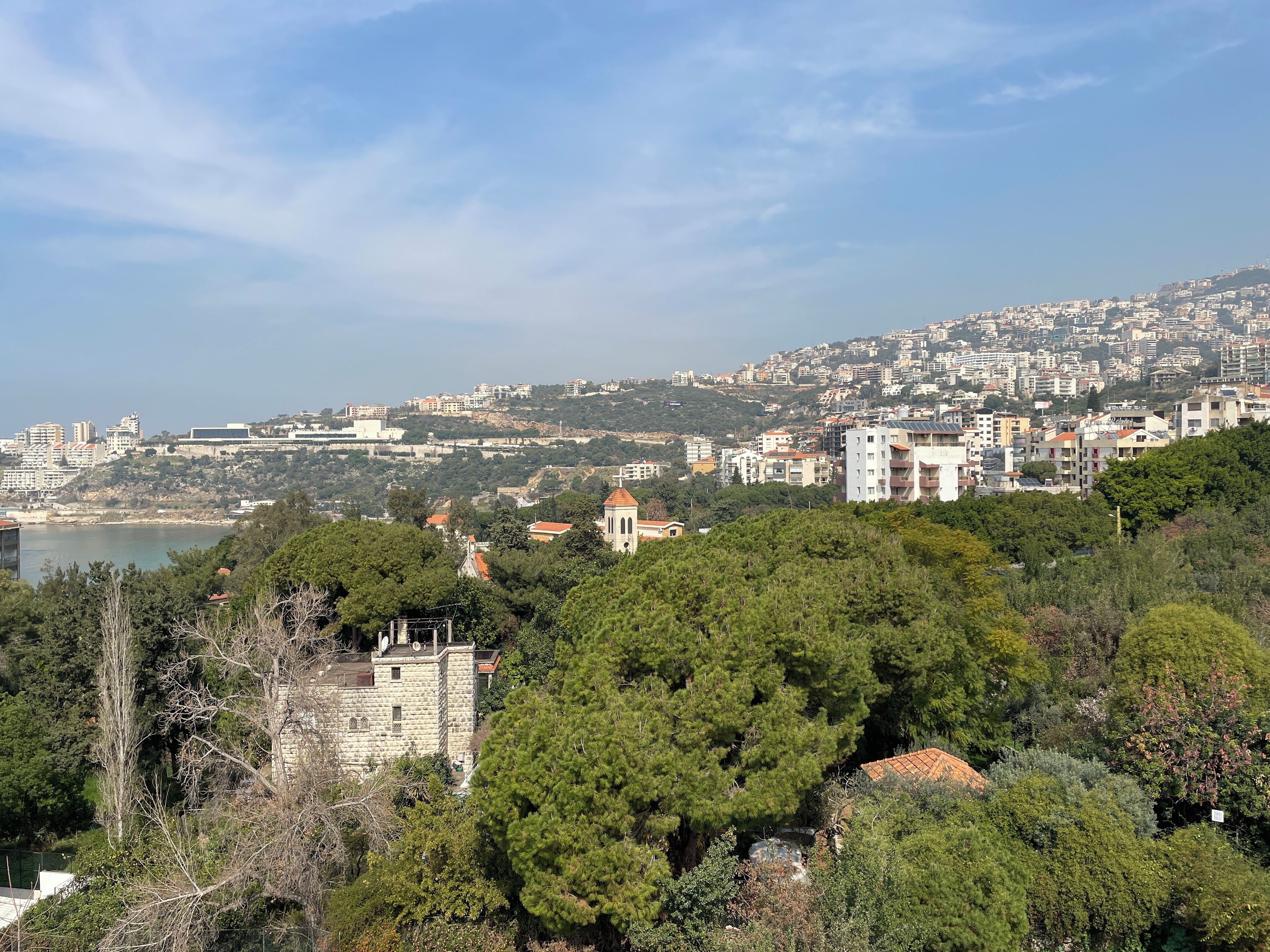 Un paysage urbain côtier caractérisé par une forte densité de constructions, une église imposante et une étendue d’eau visible au loin.