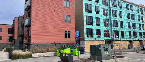 A multi-story building with a red facade and a blue facade, a parking sign, and a disabled parking sign.