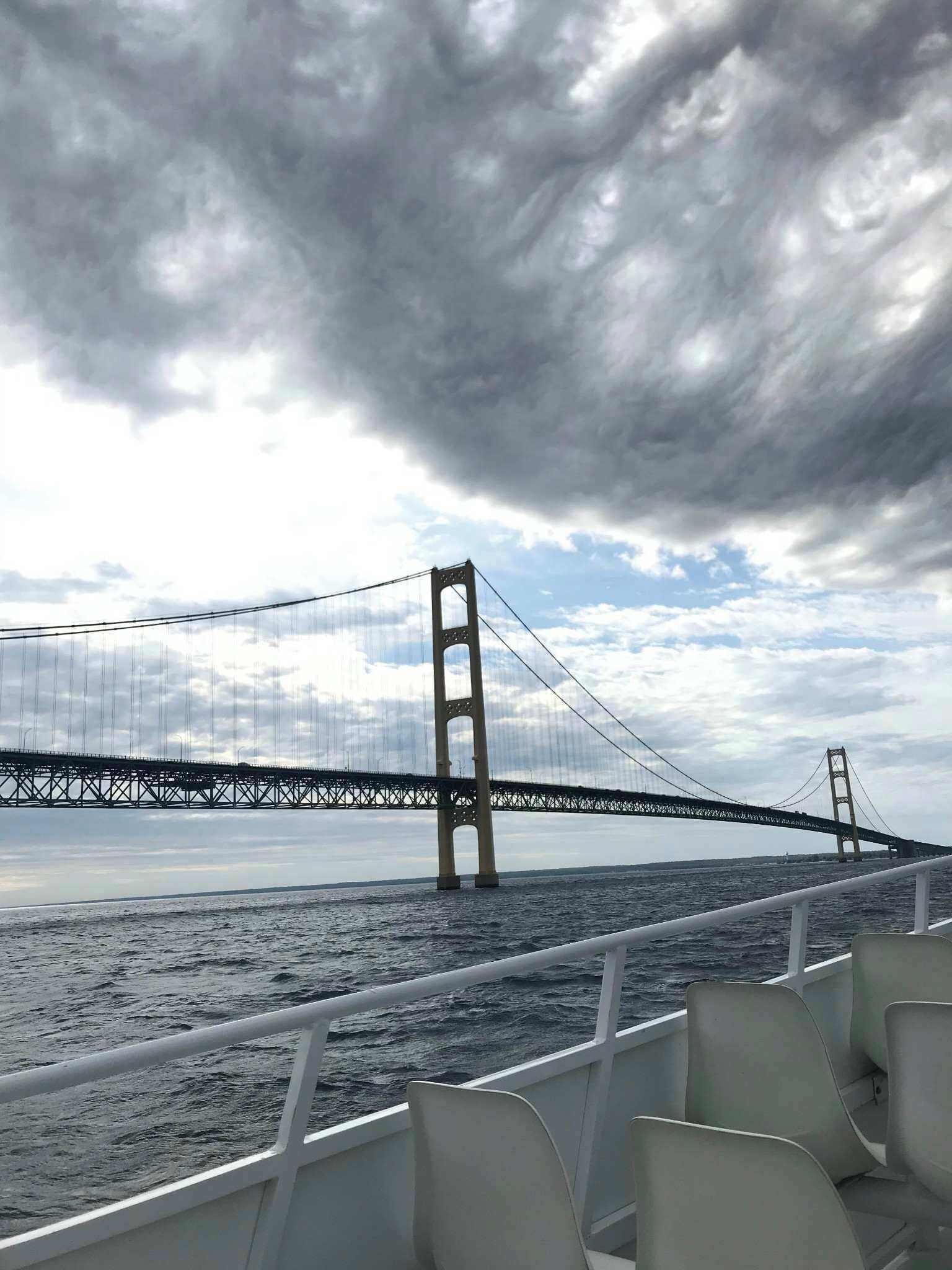 A view of a bridge from a boat with white chairs in the foreground.