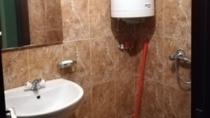 Ein Badezimmer mit Toilette, Waschbecken, Dusche und Warmwasserbereiter.