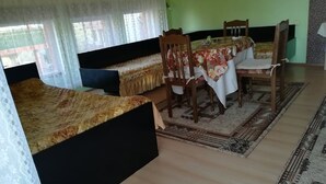 Ein Zimmer mit zwei Betten, einem Esstisch mit Stühlen und einem gemusterten Teppich.