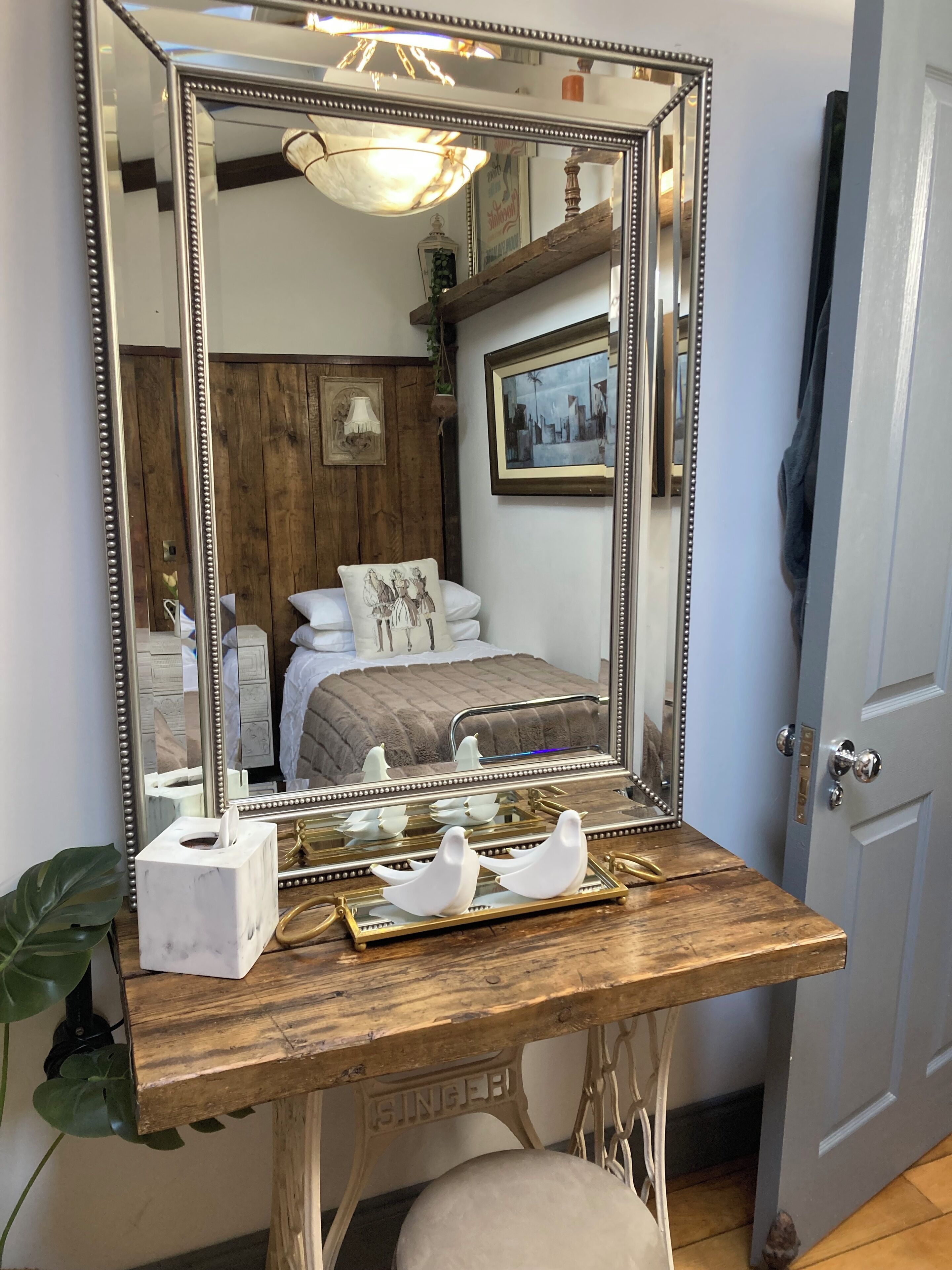 A vanity with a large mirror, a tissue box, and decorative bird figures.