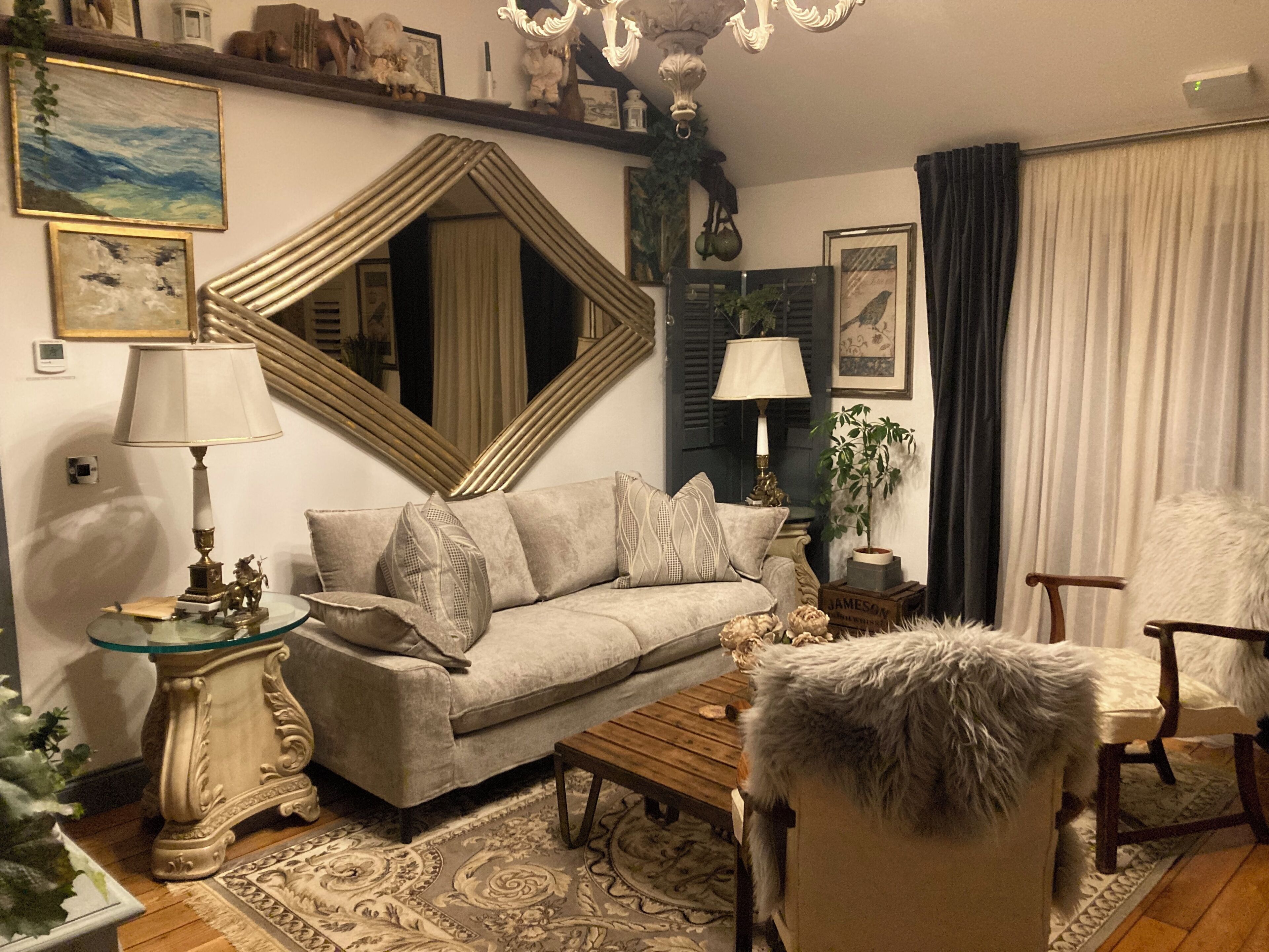 A cozy living room with a sofa, armchairs, a coffee table, and a large mirror.