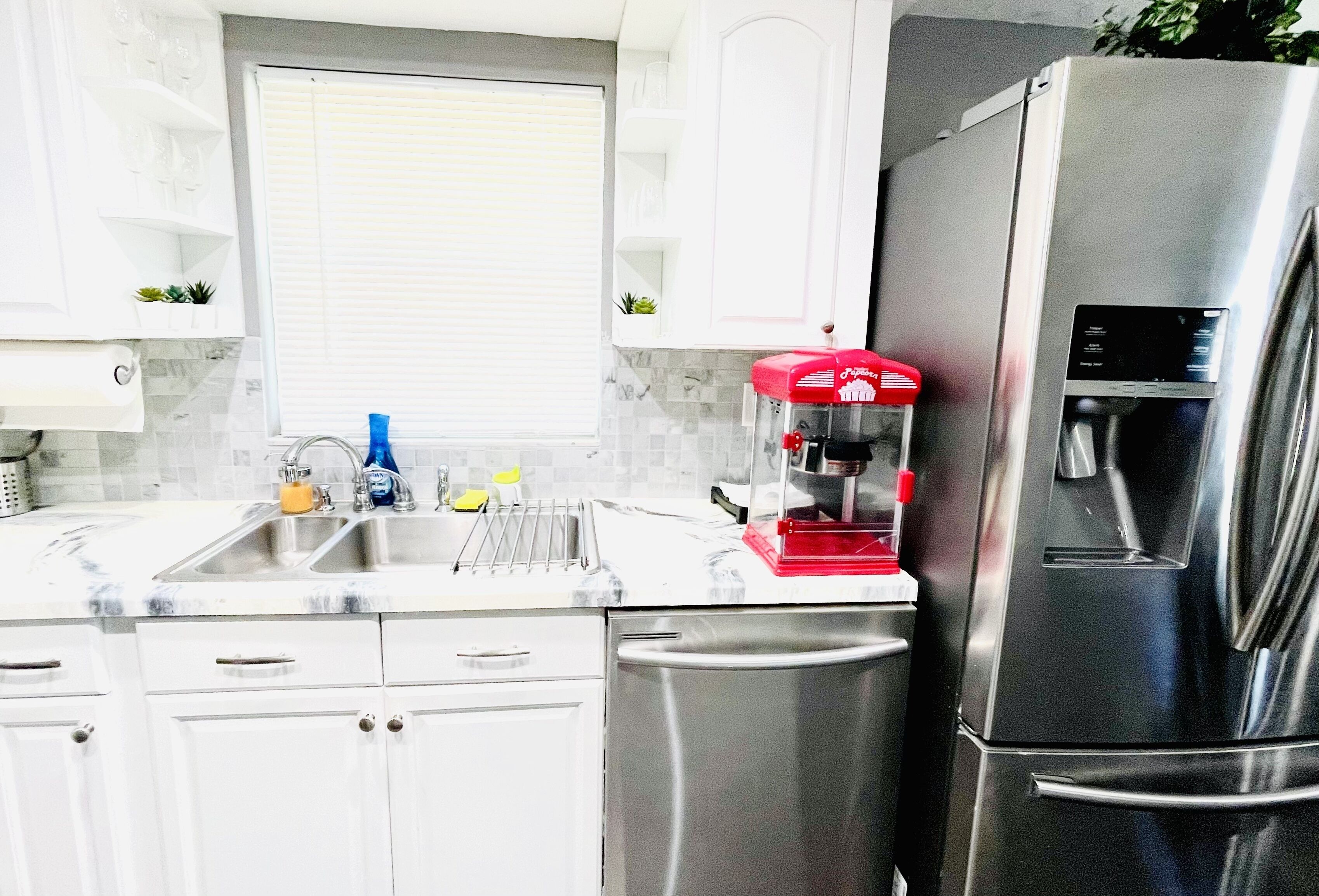 Una cucina moderna con elettrodomestici in acciaio inossidabile, tra cui un frigorifero e una macchina per il caffè.