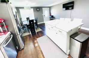 Uma cozinha moderna com uma ilha grande, eletrodomésticos de aço inoxidável e uma televisão de tela plana na parede.