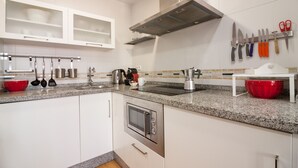 Eine moderne Küche mit weißen Schränken, einer Arbeitsplatte aus Granit, Edelstahlgeräten und einem Messerblock.