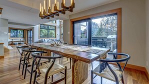 Une cuisine spacieuse avec un grand îlot central en bois, des chaises modernes et un lustre.