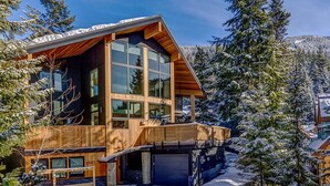 Une maison moderne en bois, dotée de grandes fenêtres et d’un garage.