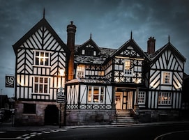 Um edifício em estilo Tudor tradicional, com uma entrada imponente e uma placa indicando um restaurante.