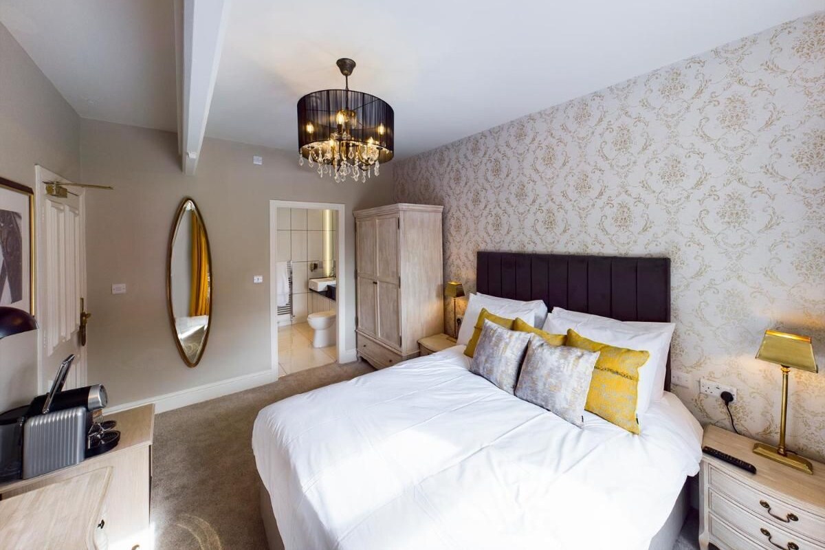 A bedroom with a large bed, a chandelier, a wardrobe, and a mirror.