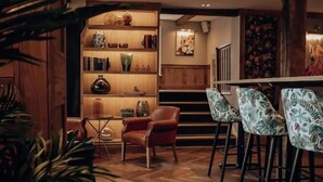 A cozy bar area with wooden flooring, a bar counter, and a seating arrangement with patterned chairs. - Lion & Swan Hotel (Congleton)
