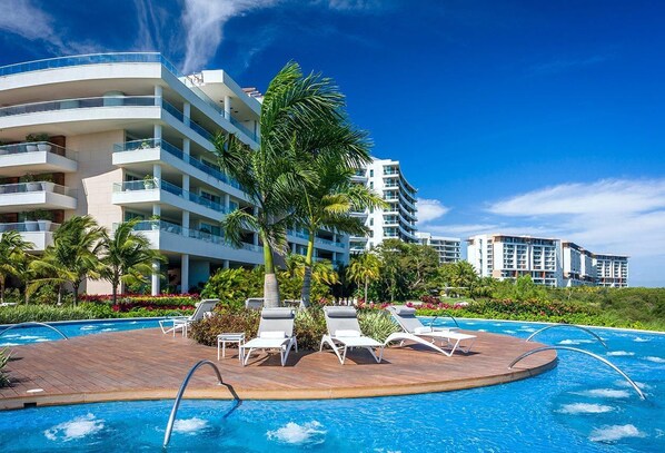 Ein Poolbereich eines Resorts mit einem runden Pool, Liegestühlen und einer Palme.