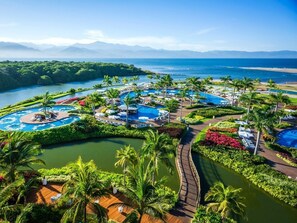 Et resort med flere swimmingpools, palmer og en flod.