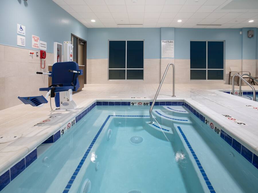 Una piscina con carriles claramente delimitados, una silla de salvavidas y las normas de la piscina exhibidas en la pared.