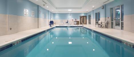 A large indoor swimming pool with clear signage indicating pool capacity and no diving allowed.