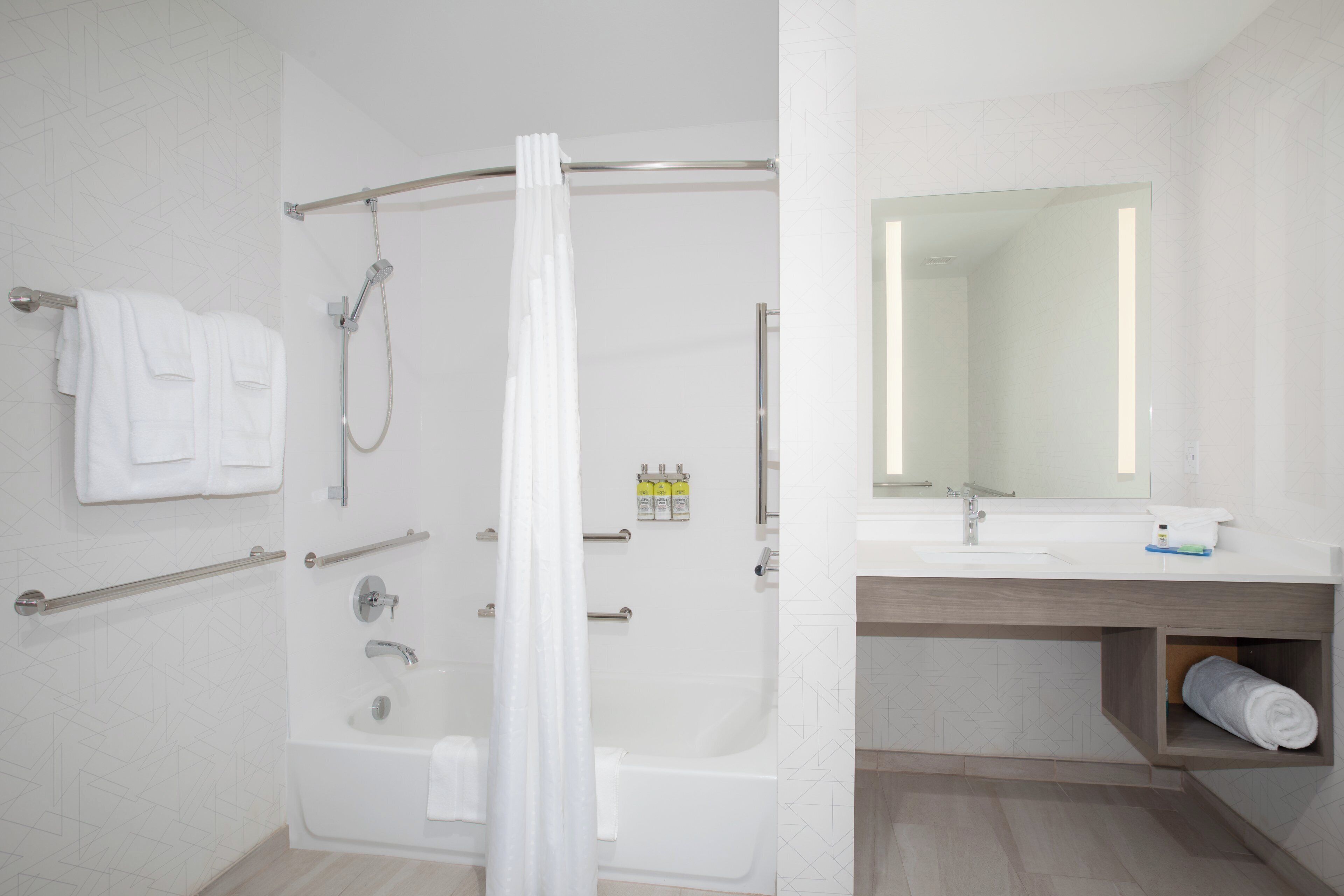 Un baño moderno con bañera, ducha y tocador con espejo.