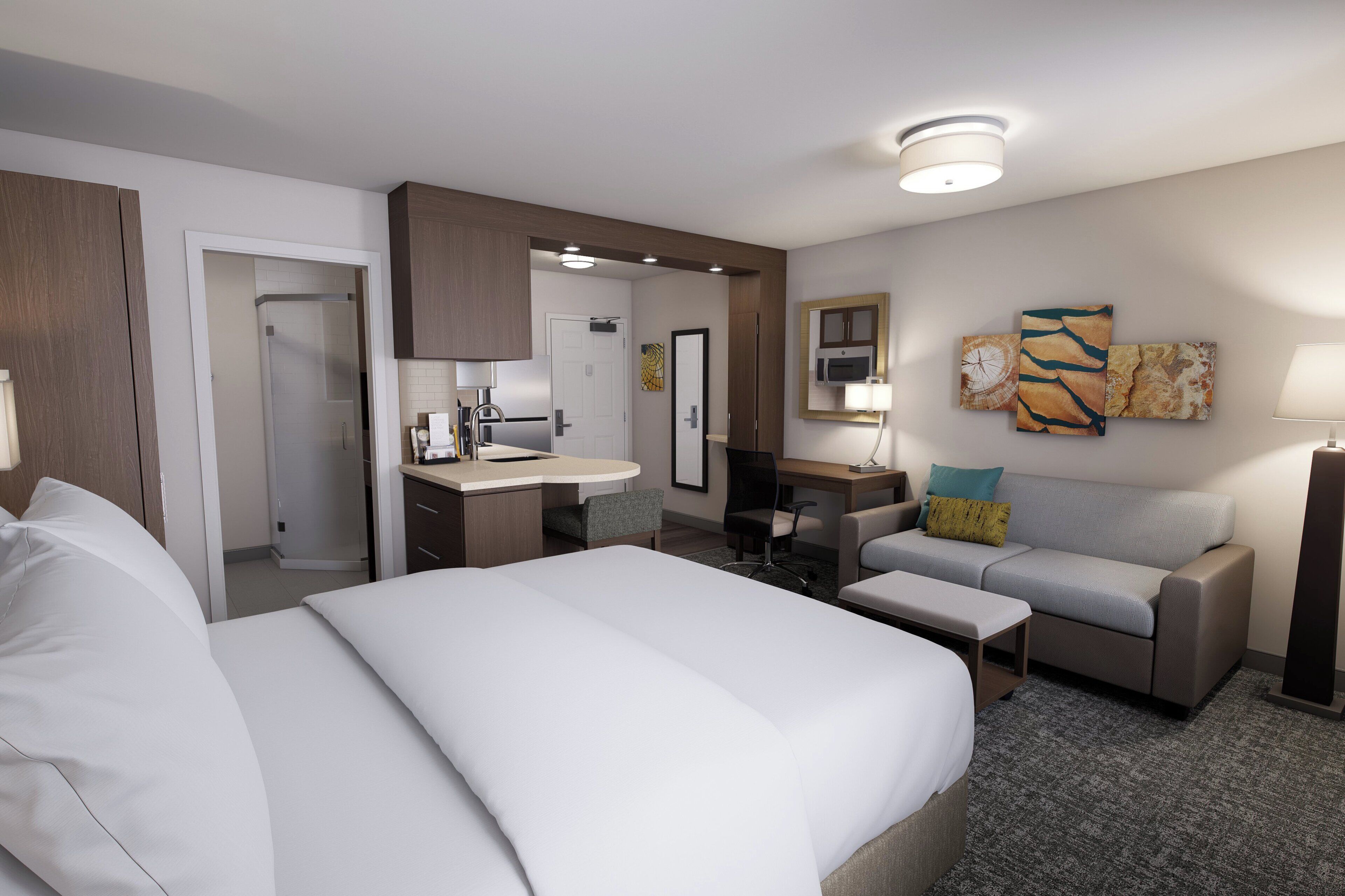 Una habitación de hotel con cama, escritorio, silla, sofá y obras de arte en las paredes.