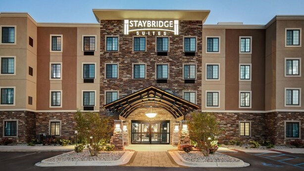 A Staybridge Suites hotel with a stone facade, multiple windows, and a prominent entrance with a covered walkway. - Staybridge Suites Southgate Detroit Area by IHG (Southgate)