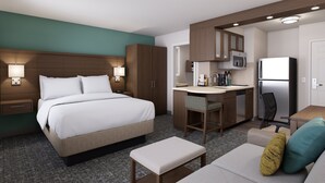 A hotel room with a bed, a desk, a chair, a refrigerator, and a microwave. - Staybridge Suites Southgate Detroit Area by IHG (Southgate)