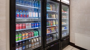 Three beverage vending machines stocked with various drinks including sodas, juices, and alcoholic beverages. - Staybridge Suites Southgate Detroit Area by IHG (Southgate)