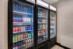 Three beverage vending machines stocked with various drinks including sodas, juices, and alcoholic beverages. - Staybridge Suites Southgate Detroit Area by IHG (Southgate)