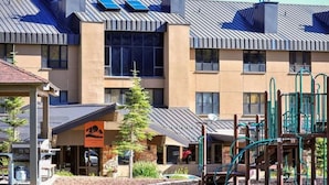 A modern building with a flat roof, large windows, and a playground area with green equipment.