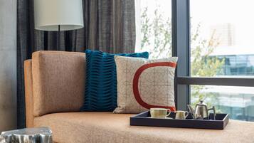 A sofa with a tray of tea set and a lamp in a room with a view of buildings.