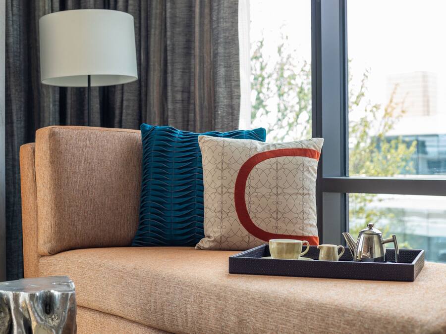 A sofa with a tray of tea set and a lamp in a room with a view of buildings.