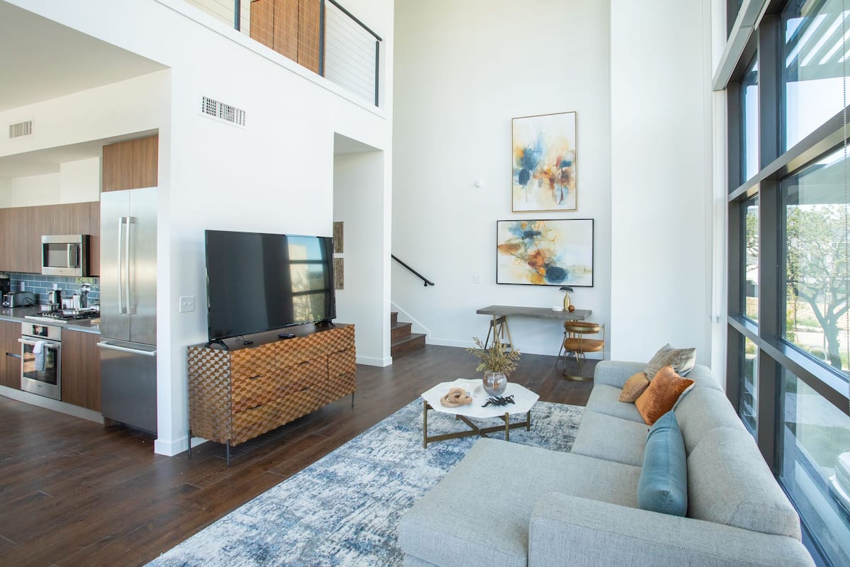 A modern living space with a kitchen, dining area, and a large window.
