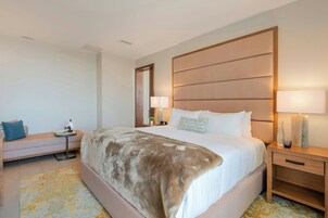 Una habitación de hotel con una cama grande, mesitas de noche, un sofá y un espejo.