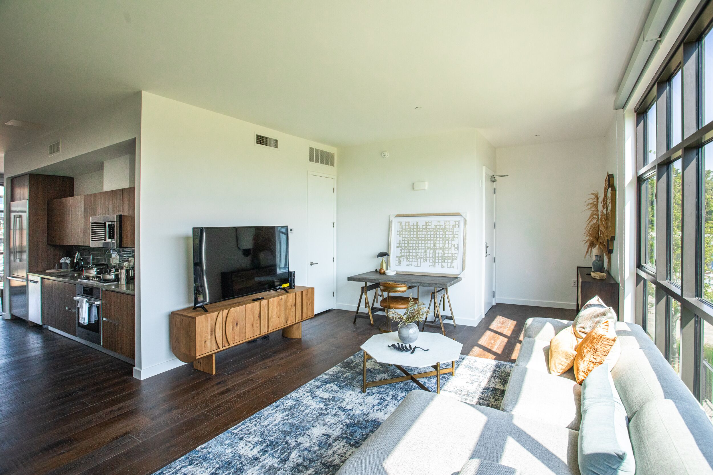 A modern living room with a flat-screen TV, a dining table, and a sofa.