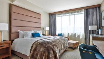Une chambre d’hôtel avec un grand lit, un bureau, une chaise et une fenêtre avec des rideaux.